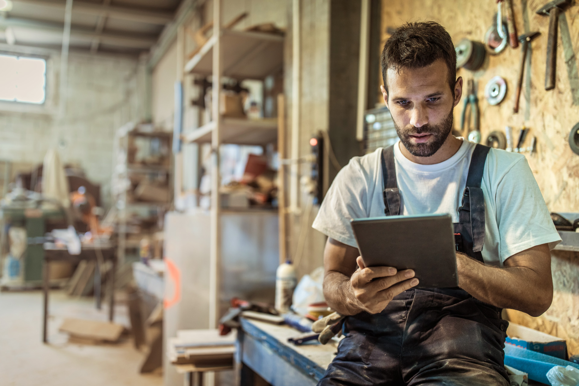 Mann in einer Werkstatt nutzt STIHL Produkt-Berater auf einem Tablet